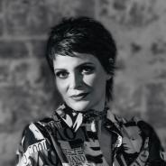 A black-and-white image of a Mexican woman looking into the camera. She has short hair and a collared shirt.